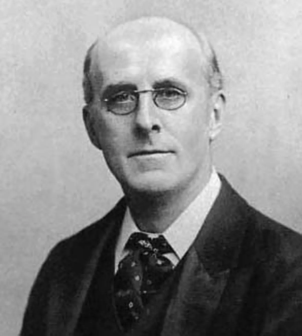 A black and white portrait of an elderly man wearing pince-nez spectacles, shown from the shoulders up.