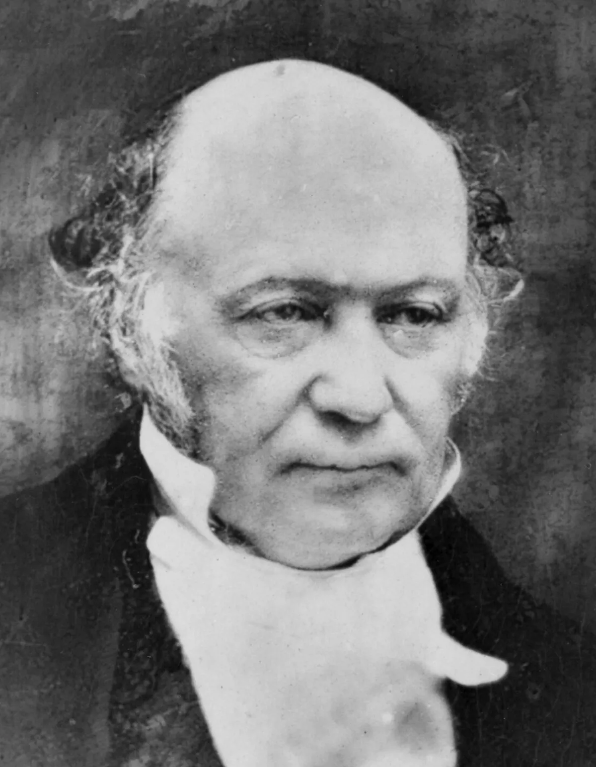 A grainy monochrome photograph of a balding older man with white side-whiskers, in a high white collar and dark coat, shown from the shoulders up.